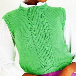 May include: A bright green knitted vest with a high neckline and a central cable knit design. The sleeveless garment is worn over a white collared shirt. The vest's texture and color suggest a handmade or vintage style.