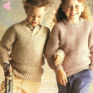 Op de afbeelding: Twee kinderen dragen gebreide truien. De jongen draagt een beige trui met een V-hals en het meisje draagt een roze trui met een ronde hals.  "Beehive Chunky Tots" staat op de zijkant van de afbeelding.