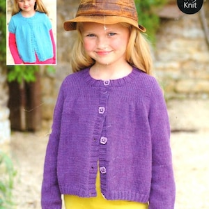 May include: A young girl wearing a purple knitted cardigan with buttons. The cardigan has long sleeves and a crew neck. The girl is wearing a yellow shirt and white trousers. The text "Easy Knit" is visible in the top right corner of the image.