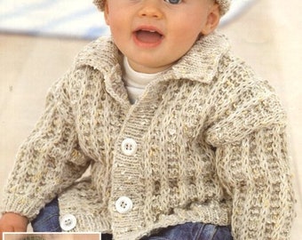 May include: A baby wearing a beige knitted cardigan with buttons and a matching knitted hat. The cardigan has a collar and the baby is wearing blue jeans.