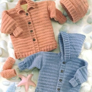 May include: Two knitted baby sweaters, one pink and one blue, with matching hats. The pink sweater has a collar and buttons down the front. The blue sweater has a hood and buttons down the front. Both sweaters have a textured knit pattern.