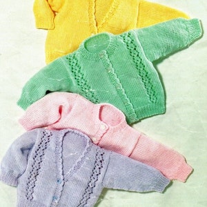 May include: Four knitted baby cardigans in different colours: yellow, green, pink, and purple. Each cardigan has a button fastening and a simple design.