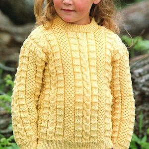 May include: A yellow knitted sweater with a cable knit pattern. The sweater has a round neckline and long sleeves.