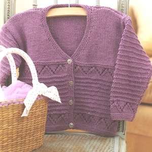 May include: A purple knitted cardigan with a V-neck and button closure. The cardigan has a lace pattern on the front and sleeves.