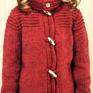 May include: A red knitted jacket with a high collar and wooden toggle fastenings. The jacket features a textured knit pattern and ribbed cuffs. The buttons are a light tan colour. A warm and cosy style.