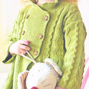 May include: A lime green knitted cardigan with wooden buttons. The cardigan features a cable knit pattern on the sleeves and front. A white stuffed toy with a red nose and striped ears is being held.