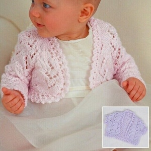 May include: A pale pink crocheted baby cardigan with a delicate lace pattern. The cardigan has a shawl collar and long sleeves.