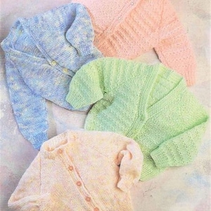 May include: Four knitted baby cardigans in different colours: light blue, light green, pink and cream. The cardigans have a simple button-up design.