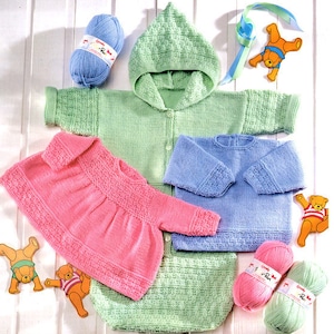 May include: Three knitted baby outfits in pink, blue, and green. The outfits are made with a textured stitch and feature a hooded cardigan, a dress, and a sweater. The outfits are displayed on a white wooden background with yarn balls and toy bears.