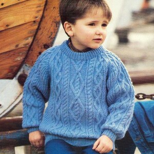 May include: A blue knitted sweater with a cable knit pattern. The sweater has a round neckline and long sleeves.