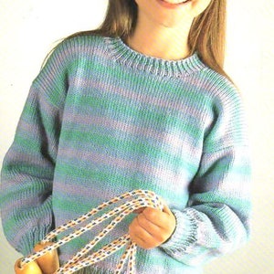 Puede incluir: Un suéter de punto a rayas azules y verdes con cuello redondo. El suéter está siendo sostenido por una persona que también sostiene una cuerda para saltar.