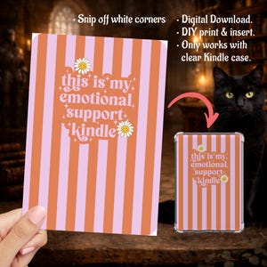 May include: A digital download for a Kindle insert with a vertical striped design in orange and pink. The text reads "this is my emotional support Kindle" with daisy accents. A clear Kindle case with the insert is also shown.