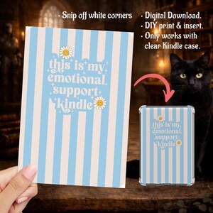 May include: A light blue and cream striped Kindle insert with the text "this is my emotional support Kindle" and daisy accents. A clear Kindle case with the insert is shown next to the insert. A black cat is in the background.