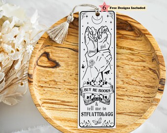 May include: A rectangular white bookmark featuring black line art of hands, a rose, a crescent moon, and an open book with the text "BUY ME BOOKS & tell me to STFUATTDLAGG". The bookmark includes a beige tassel and a "6 Free Designs Included" label.