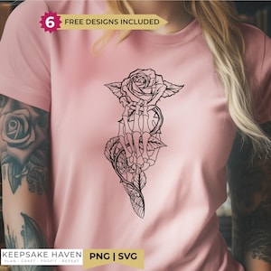 May include: A light pink t-shirt featuring a black line art graphic of a skeletal hand holding a rose with thorny stems and a spiderweb pattern. A banner at the top reads 6 FREE DESIGNS INCLUDED, and a bottom label reads KEEPSAKE HAVEN PNG | SVG.