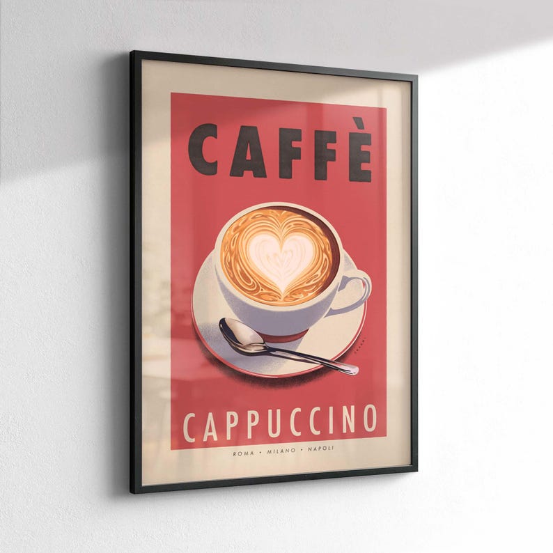 Op de afbeelding: Ingelijste kunstafdruk met een cappuccino met hartvormige latte art. Het woord "CAFF&Egrave;" staat bovenaan, met "CAPPUCCINO" eronder. De print heeft een rode achtergrond, een witte kop en schotel en een zilveren lepel.
