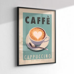 Op de afbeelding: Ingelijste kunstprint met een cappuccino met hartvormige latte art. Het woord "CAFF&Egrave;" staat bovenaan, met "CAPPUCCINO" eronder. De print heeft een blauwgroene achtergrond en een zwart frame. De onderkant van de print luidt "ROMA &bull; MILANO &bull; NAPOLI."
