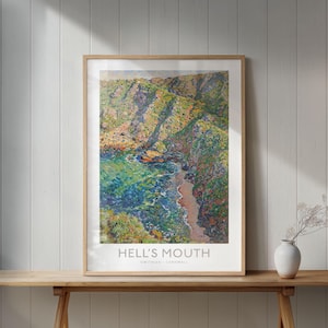 Könnte beinhalten: Ein gerahmter Druck von Hell's Mouth, Cornwall, mit einer farbenfrohen Küstenlandschaft. Das Kunstwerk zeigt eine Klippe, türkisfarbenes Wasser und einen Sandstrand. Der Druck wird auf einem Holztisch ausgestellt. Der Text 'Hell's Mouth' ist sichtbar.