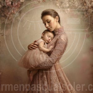 Puede incluir: Una mujer sostiene a un bebé dormido, ambos vestidos de rosa. La mujer lleva un vestido de manga larga con detalles de encaje. El fondo presenta un arco floral de rosas rosas y otras flores, creando una escena suave y romántica.