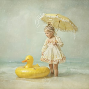 Puede incluir: Una niña pequeña está de pie en aguas poco profundas, sosteniendo un parasol amarillo. La niña lleva un vestido color crema con detalles florales. Un gran flotador inflable con forma de pato amarillo flota cerca. La escena evoca un día soleado en la playa.