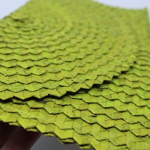 May include: A set of green woven placemats made from natural materials. The placemats are woven in a tight pattern and have a slightly textured surface.