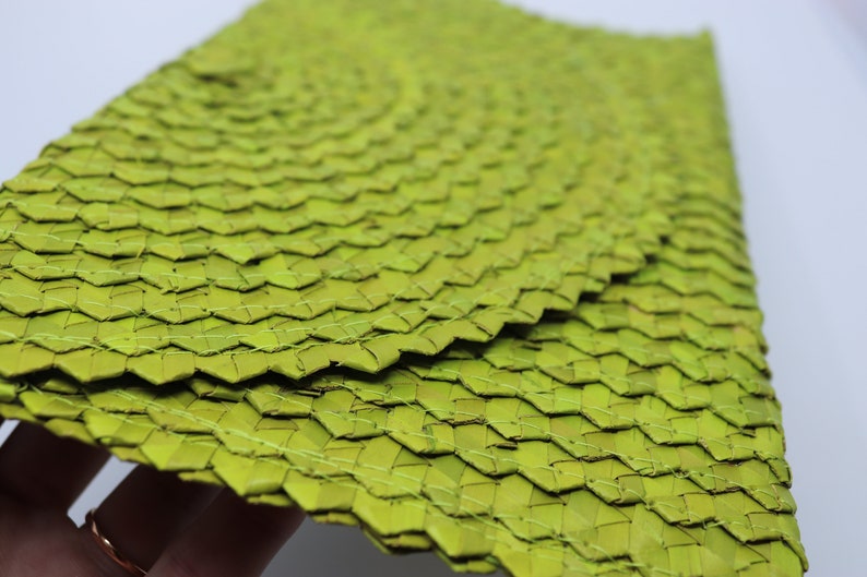 May include: A set of green woven placemats made from natural materials. The placemats are woven in a tight pattern and have a slightly textured surface.