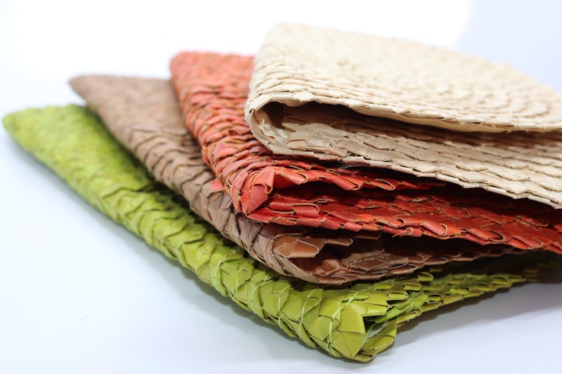 May include: Stack of four woven placemats in green, brown, orange, and beige.