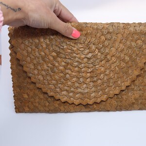 May include: A brown woven clutch bag with a distinctive geometric pattern.