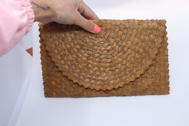 May include: A brown woven clutch bag with a distinctive geometric pattern.