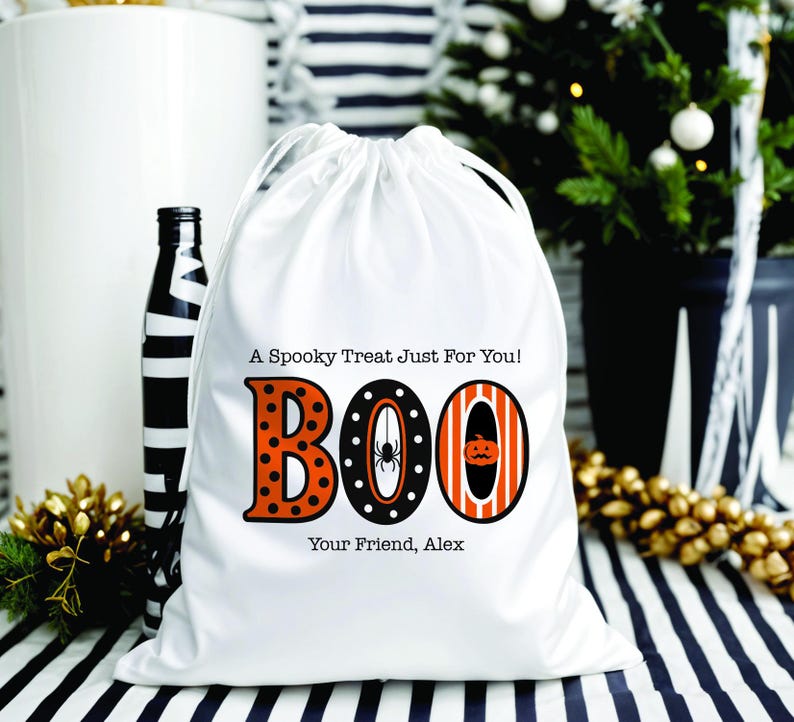 May include: White drawstring bag with the word "BOO" in orange and black, with a spider and pumpkin design. Text on the bag reads "A Spooky Treat Just For You!" and "Your Friend, Alex". A black and white striped bottle is to the left.