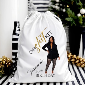 May include: White drawstring bag with gold glitter text that reads "OH shit KIT" and "Jasmine's 30th BIRTHDAY". The bag features a photo of a woman in a black blazer and metallic pants. A black and white striped bottle is visible.