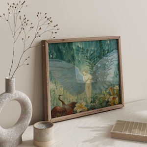 May include: A framed art print featuring a nude figure with large blue wings, set against a backdrop of lush greenery and flowers. The artwork is in a wooden frame, with a vase and candle in the foreground.