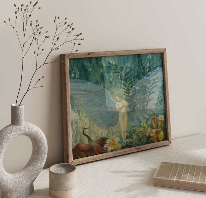 May include: A framed art print featuring a nude figure with large blue wings, set against a backdrop of lush greenery and flowers. The artwork is in a wooden frame, with a vase and candle in the foreground.