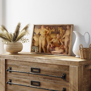 May include: A framed artwork depicting nude figures in a classical style, displayed on a wooden dresser. The dresser has three drawers with black metal handles. A vase with dried plants and a white pitcher with a small basket are also on the dresser.