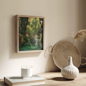 May include: A framed artwork depicts a group of figures dancing in a forest setting, with green and yellow hues dominating the scene. The artwork is in a light-colored wooden frame, hanging on a neutral-toned wall. A candle, a book, a woven tray, and a vase are also visible.