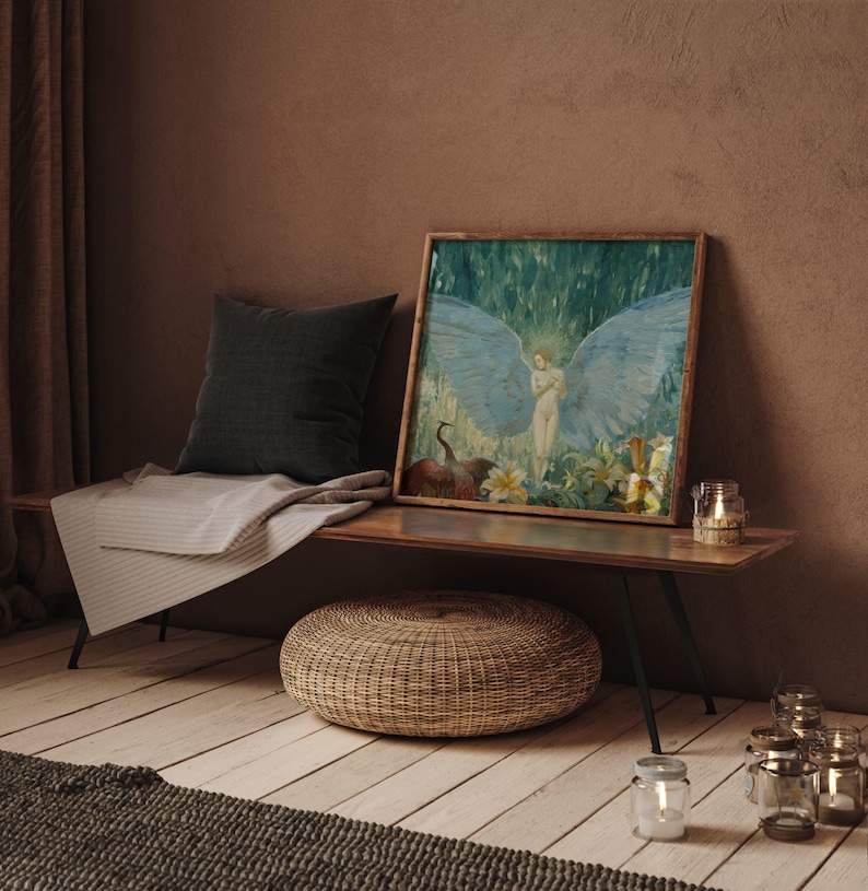 May include: A framed artwork depicting a nude figure with large blue wings, set against a backdrop of green foliage. The artwork is displayed on a wooden bench with a dark gray pillow, a striped blanket, and a woven ottoman. Several glass candle holders are also present.