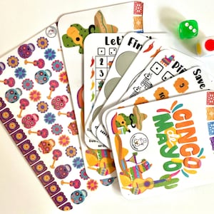 May include: A selection of colourful Cinco de Mayo themed cards and dice. The cards feature illustrations of cacti, guitars, and floral patterns. The text "Cinco de Mayo" is visible on one card. Two dice with red and green dots are also present.