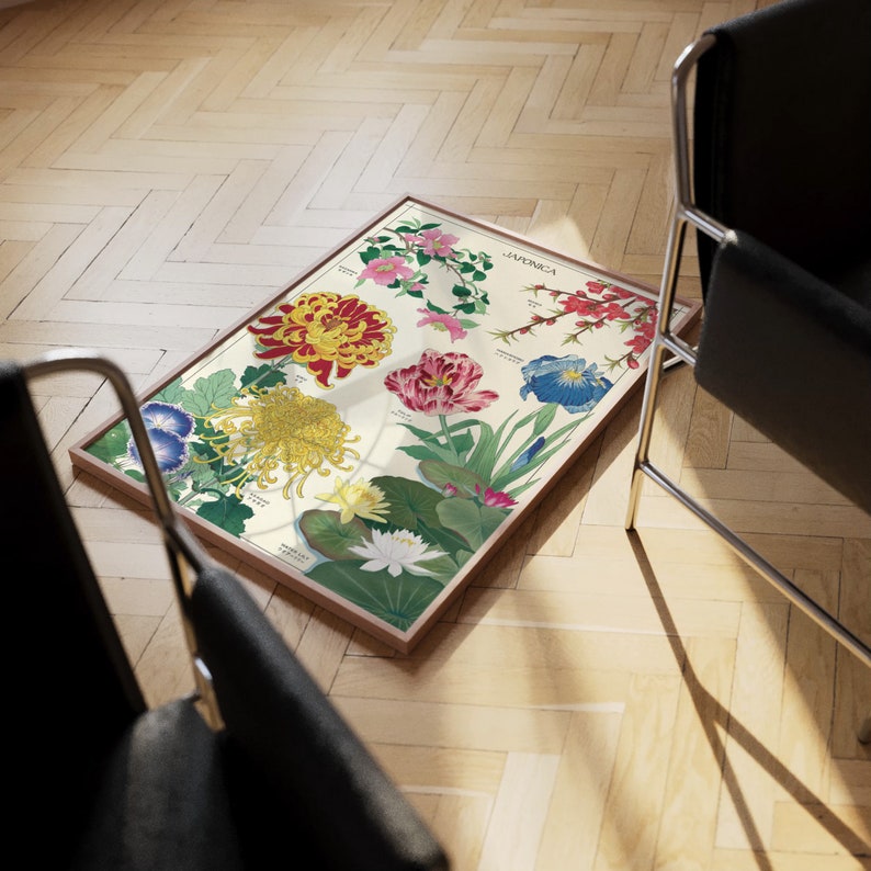Puede incluir: Una impresi&oacute;n bot&aacute;nica vintage que ilustra una variedad de flores en tonos rojos, rosas, azules, amarillos y blancos. La impresi&oacute;n se titula "Japonica" y est&aacute; enmarcada en un marco de madera claro.