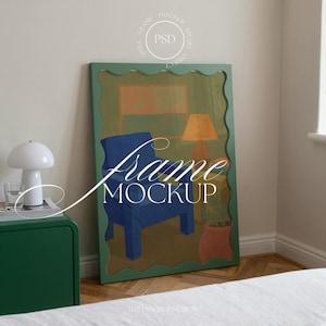 Peut inclure: Une impression d'art encadrée représentant une chaise bleue, une lampe orange et un pot en terre cuite avec une plante. Le cadre est vert avec un bord ondulé. Les mots "Frame Mockup" sont écrits sur l'image.