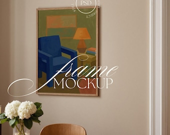 Puede incluir: Una impresión artística enmarcada que presenta una escena interior abstracta con una silla azul, una lámpara naranja y un fondo verde. La obra de arte está en un marco de madera. Las palabras "Frame Mockup" están superpuestas en la imagen.