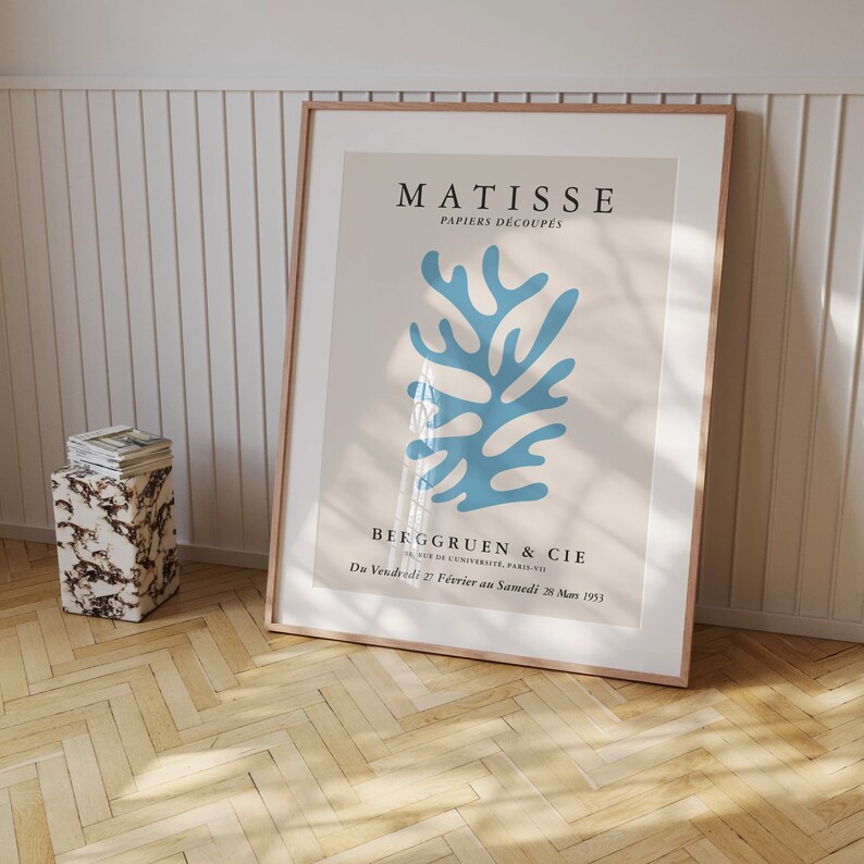 May include: A framed poster with a blue abstract design by Henri Matisse. The poster is titled "Matisse Papiers D&eacute;coup&eacute;s" and features the text "Berggruen & Cie" and "Du Vendredi 27 F&eacute;vrier au Samedi 28 Mars 1953".