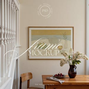 Puede incluir: Una obra de arte enmarcada con una naturaleza muerta cuelga de una pared beige. Una mesa de madera exhibe un jarrón con flores blancas, un plato de cerezas y una servilleta doblada. El texto "Frame Mockup" está superpuesto.