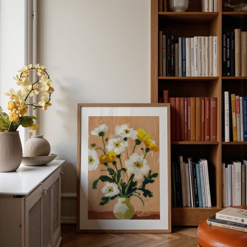 Portrait wooden frame mockups leaning against an oak bookcase in a cozy Scandinavian-style reading nook — soft natural window light, hardwood floor, decorative vases and orchids on a console; styled home decor and print mockups for listings.