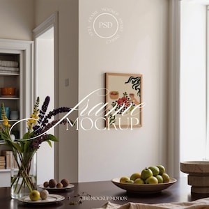 Può includere: Un'opera d'arte incorniciata con una cornice in legno chiaro è appesa a una parete color crema. L'opera presenta una natura morta con frutta e un motivo a scacchi. Un vaso di fiori e una ciotola di mele verdi sono su un tavolo di legno scuro.