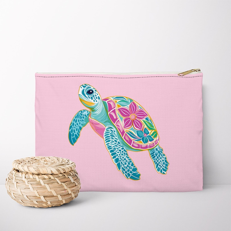 Op de afbeelding: Een roze etui met rits met een kleurrijk bloemmotief van een zeeschildpad.