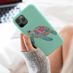 Op de afbeelding: Een mintgroene telefoonhoes met een kleurrijk, bloemig patroon van een zeeschildpad.