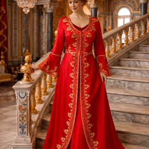 Könnte beinhalten: Ein langes, rotes Kleid mit goldener Stickerei. Das Kleid hat einen V-Ausschnitt, lange Ärmel mit ausgestellten Manschetten und einen dekorativen Goldbesatz. Das Kleid wird auf einer Marmortreppe in einer großen Halle getragen.