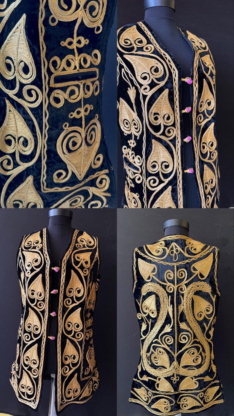 May include: Black velvet vest with gold-coloured embroidered floral and scrollwork design. The vest features a V-neck, pink button closures, and a detailed pattern on the front and back. The vest is displayed on a mannequin.