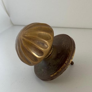 Puede incluir: Un pomo de puerta de latón con una parte superior abovedada estriada y una base redonda.