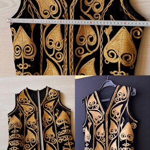 May include: Black vest with gold embroidery. The vest features an intricate design of swirling patterns and leaf-like shapes. The vest measures approximately 117 cm in length.